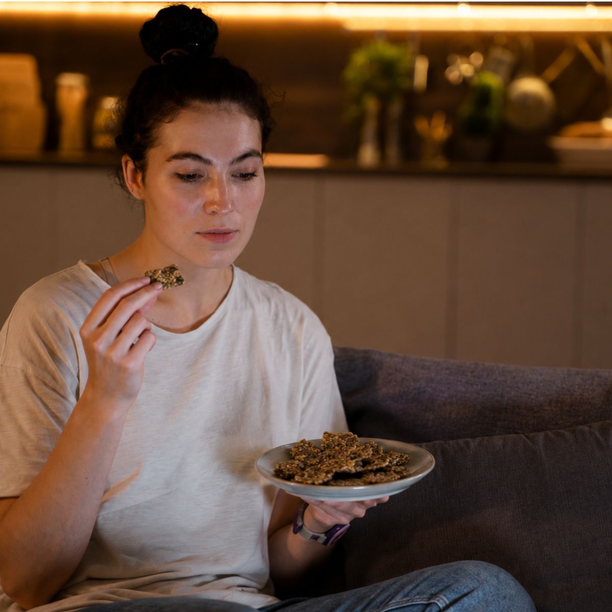 Woman enjoying Njammies Seed Crackers while relaxing at home.