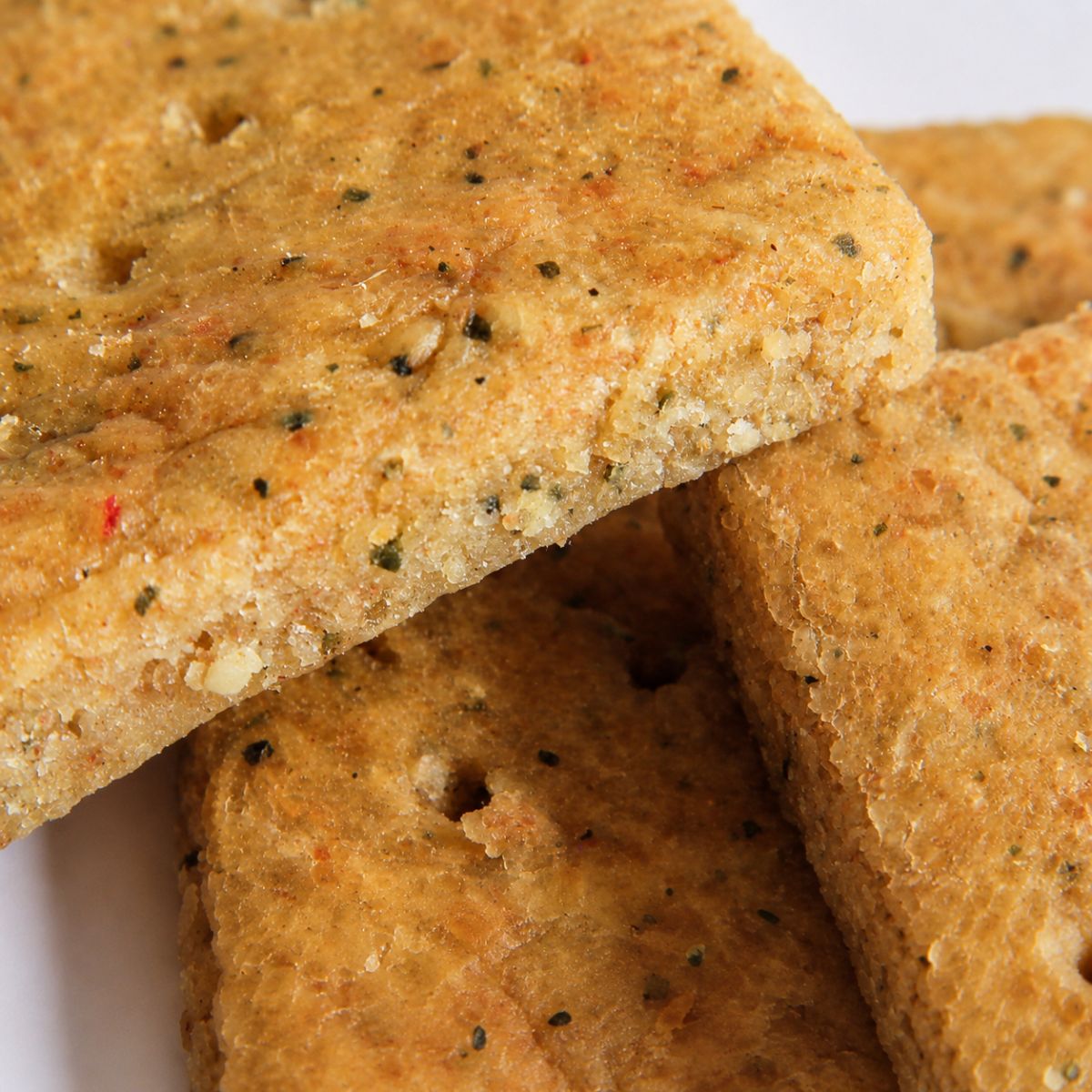 Close-up of crisp Njammies Lentil & Herb Crackers with visible herbs and seeds.