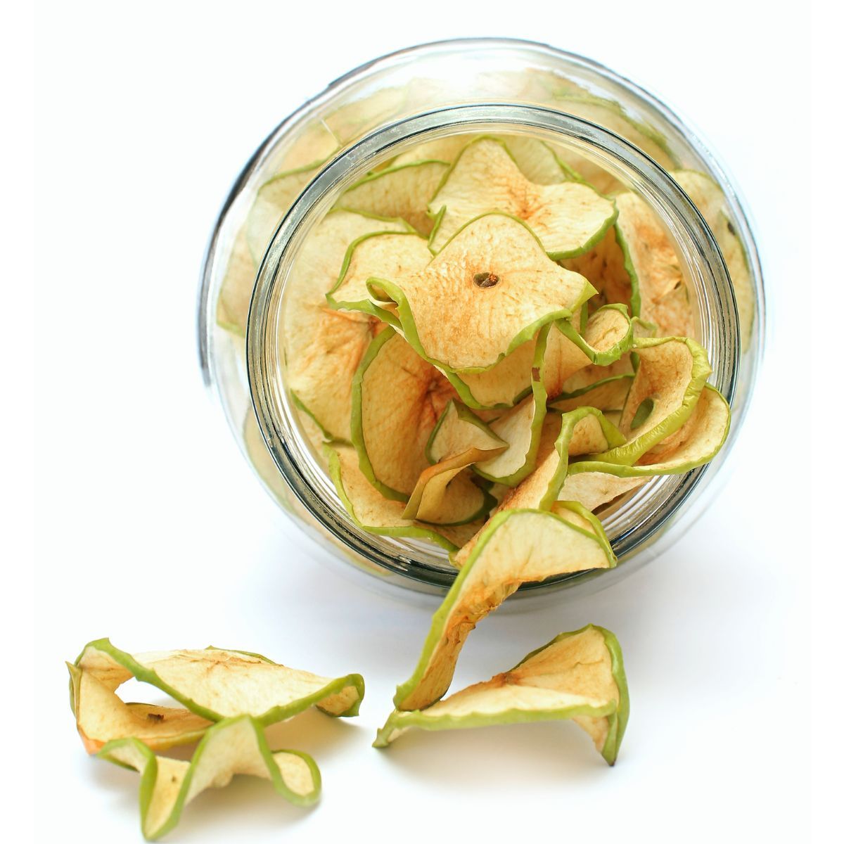 Naturally dried apple slices displayed in and around a glass jar.
