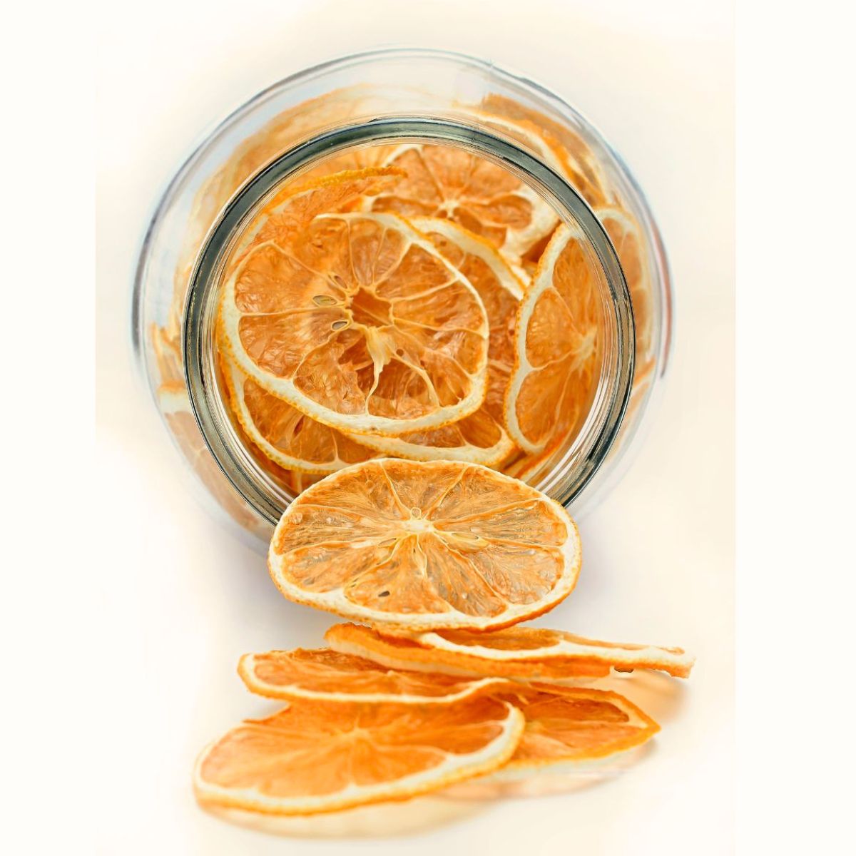 Naturally dried orange slices displayed in and around a glass jar.